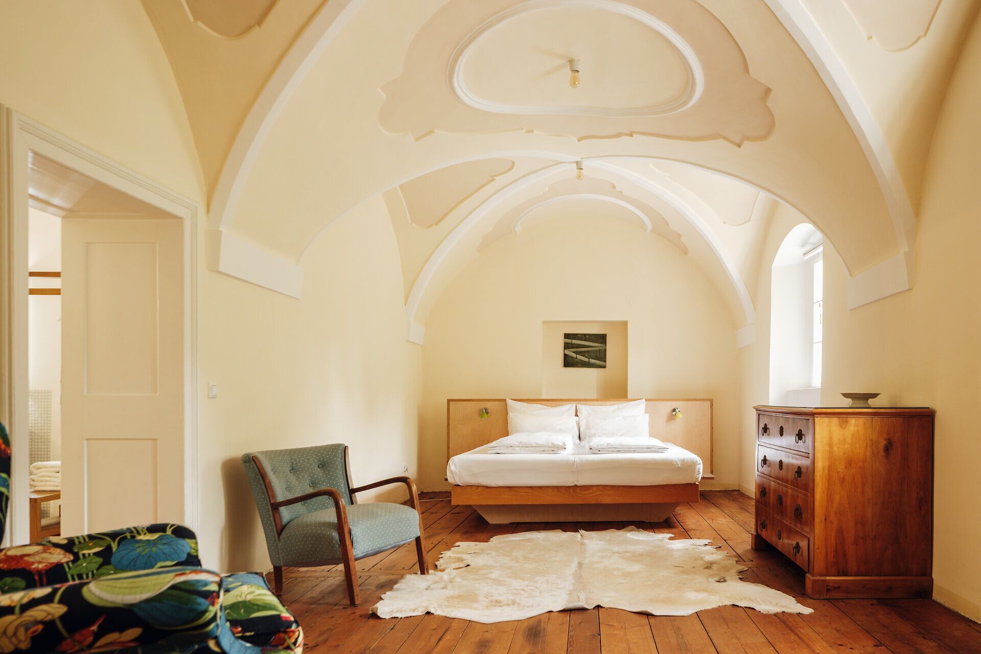 Helles Schlafzimmer mit Bett, Kommode und Couch-Sessel