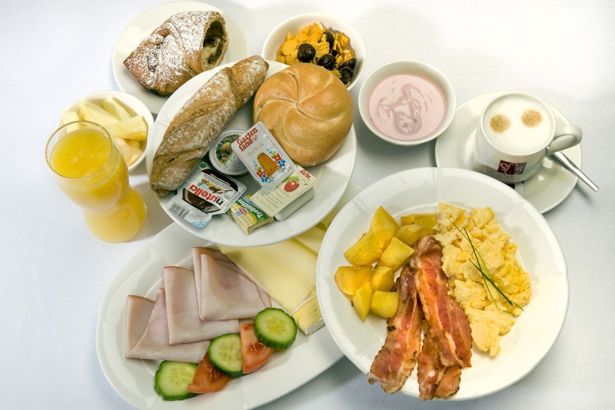 Diverses Essen vom Frühstücksbuffet auf Tellern angerichtet.