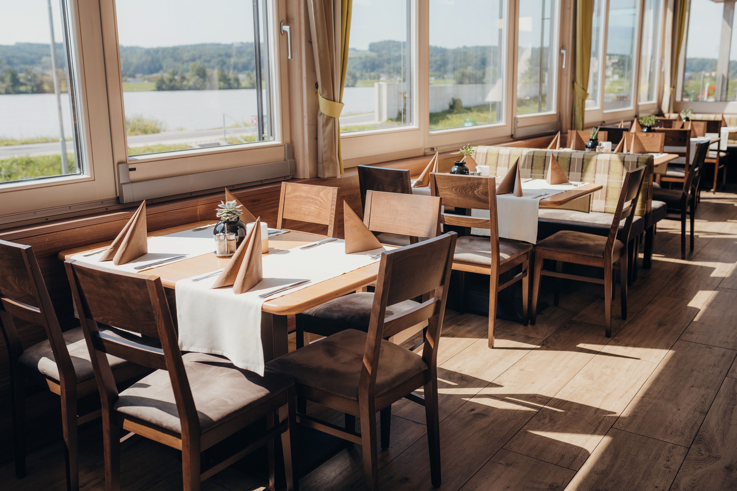 Helles Restaurant mit Holzmöbeln und Blick auf die Donau.