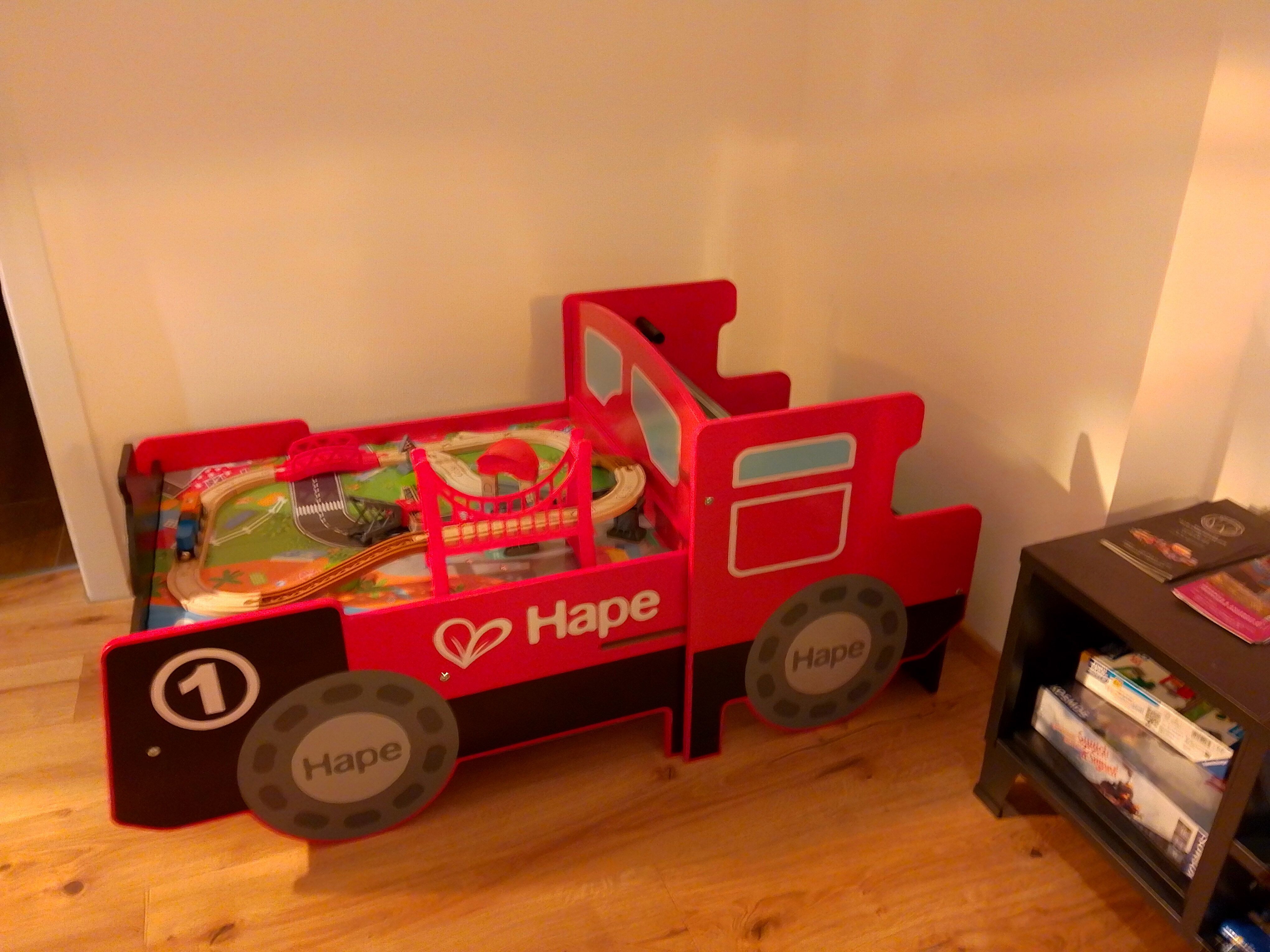 Rotes Spielzeugbett in Form einer Lokomotive mit Spielzeugeisenbahn.