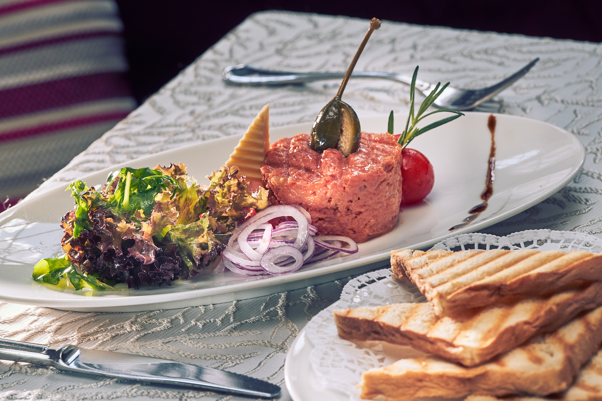 Ein köstliches Beef Tatar, kunstvoll angerichtet mit frischen Zwiebelringen und knusprigem Toast, lädt zu einem genussvollen Moment ein. Umgeben von der malerischen Kulisse der Donau, bietet das Wirtshaus eine perfekte Gelegenheit, die regionale Wirtshauskultur zu erleben.
