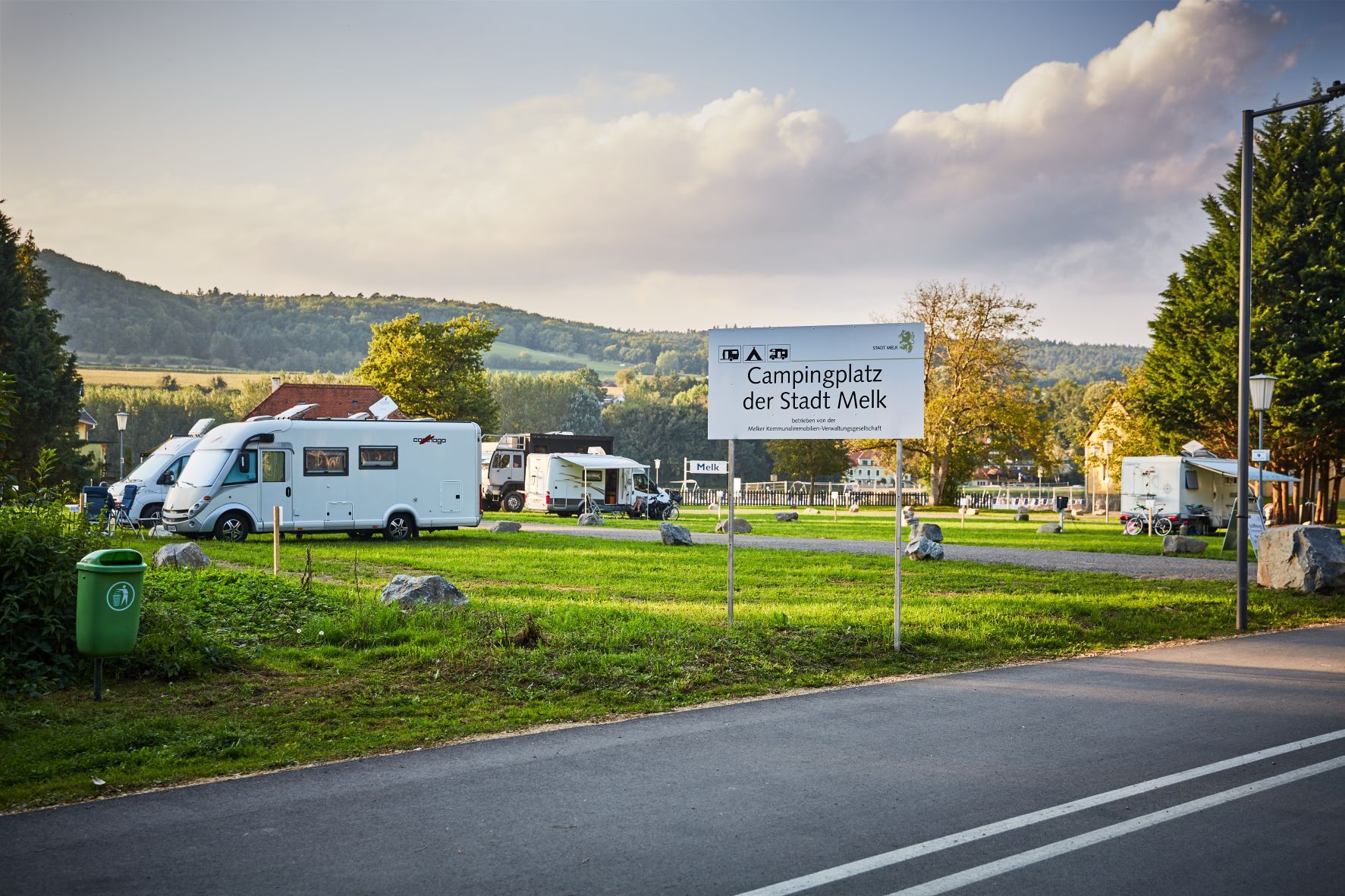 Campingplatz in Melk mit Wohnmobilen und einem Schild im Vordergrund.