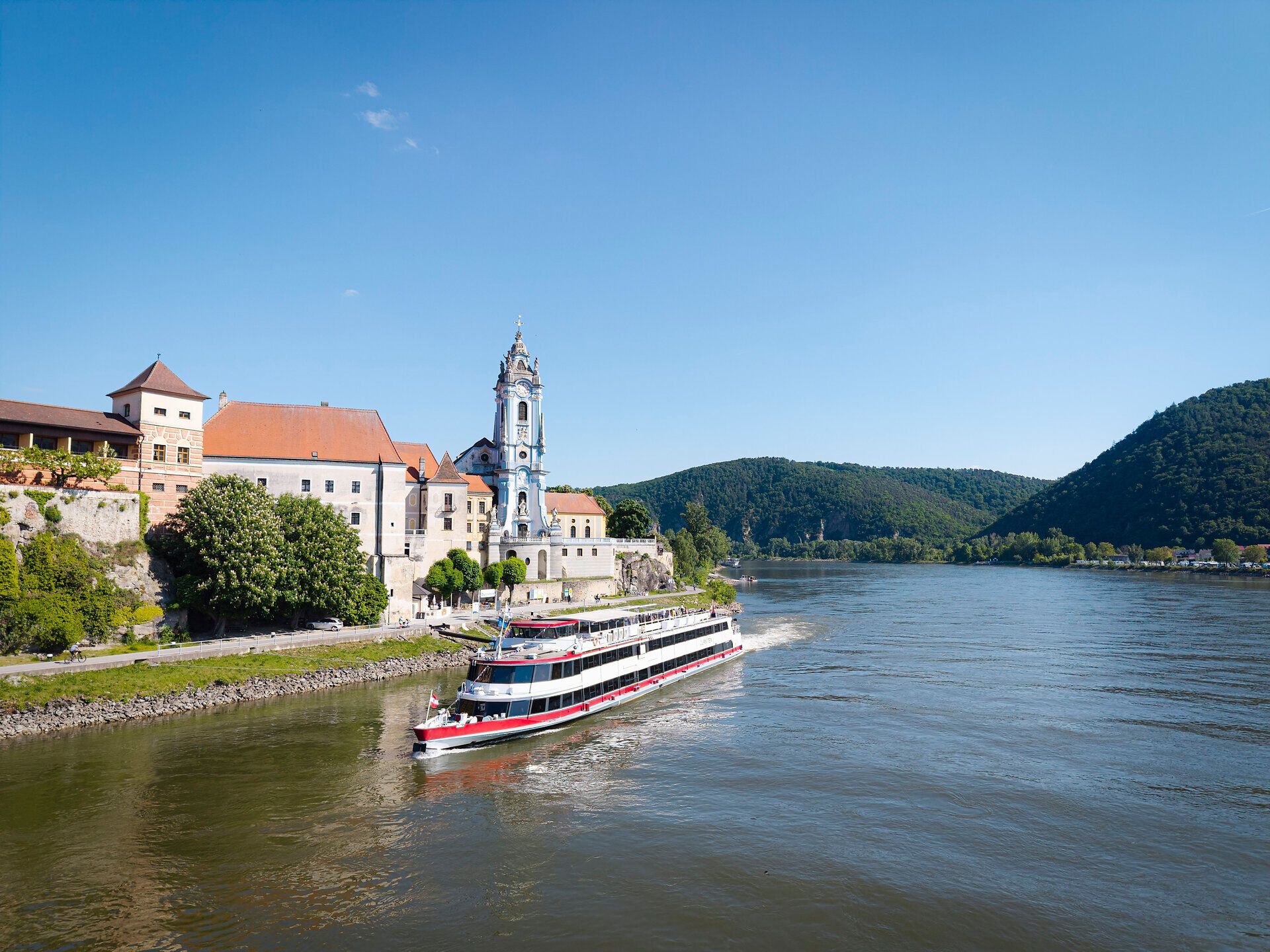 Ein Schiff fährt auf der Donau und im Hintergrund ist Dürnstein zu sehen.