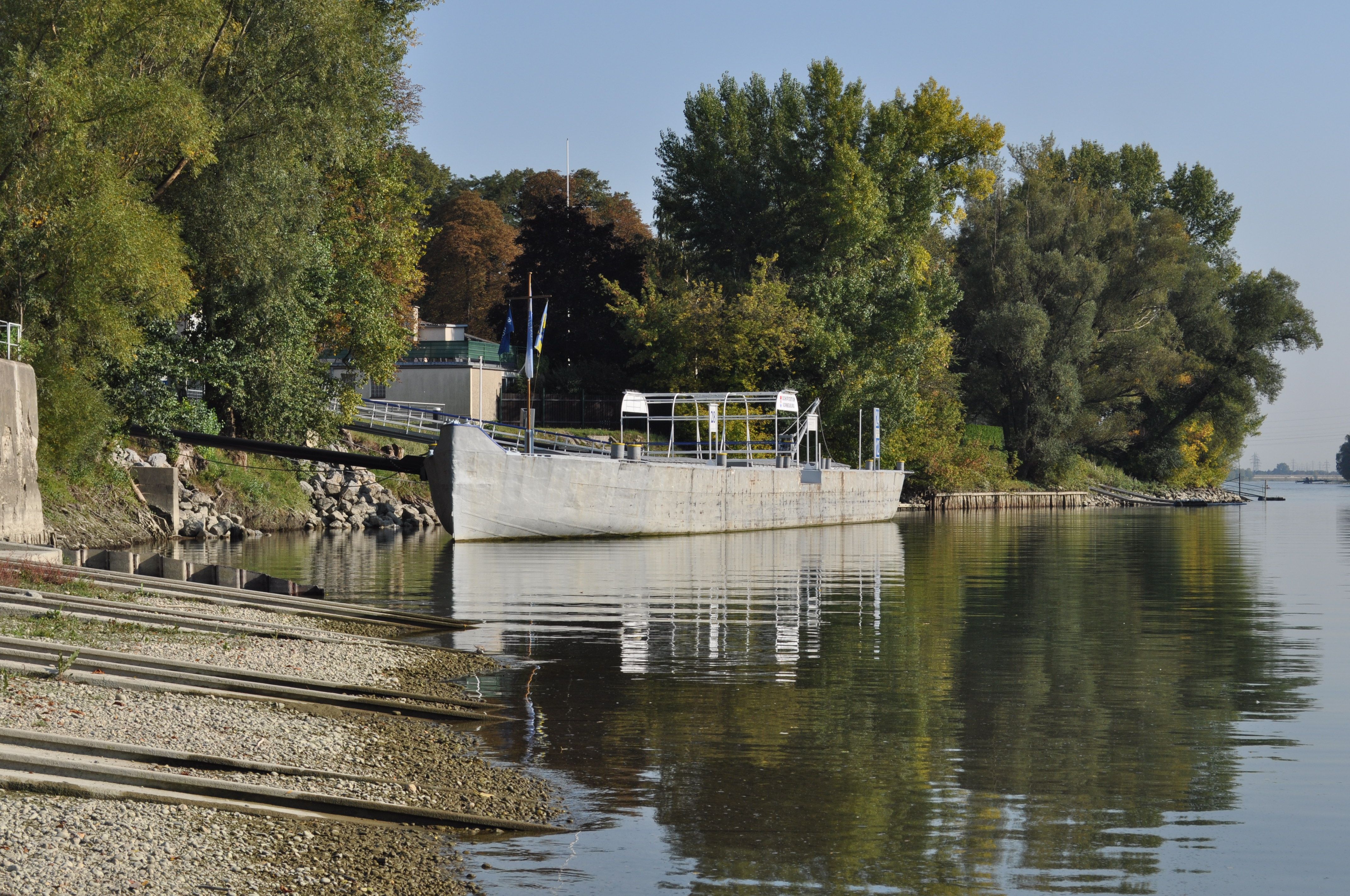 Schiffsanlegestelle an einem Fluss mit Bäumen im Hintergrund.