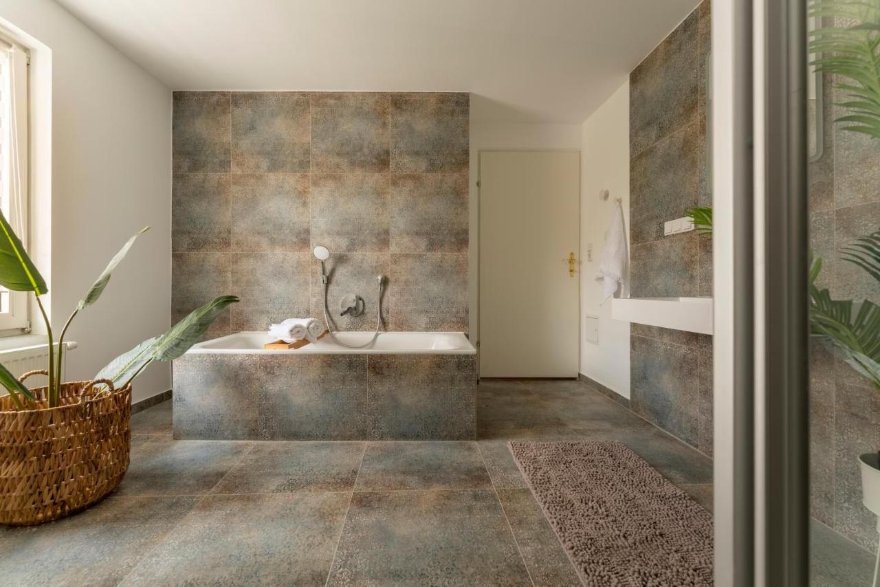 Modernes Badezimmer mit Badewanne, Pflanzen und Handtuch.