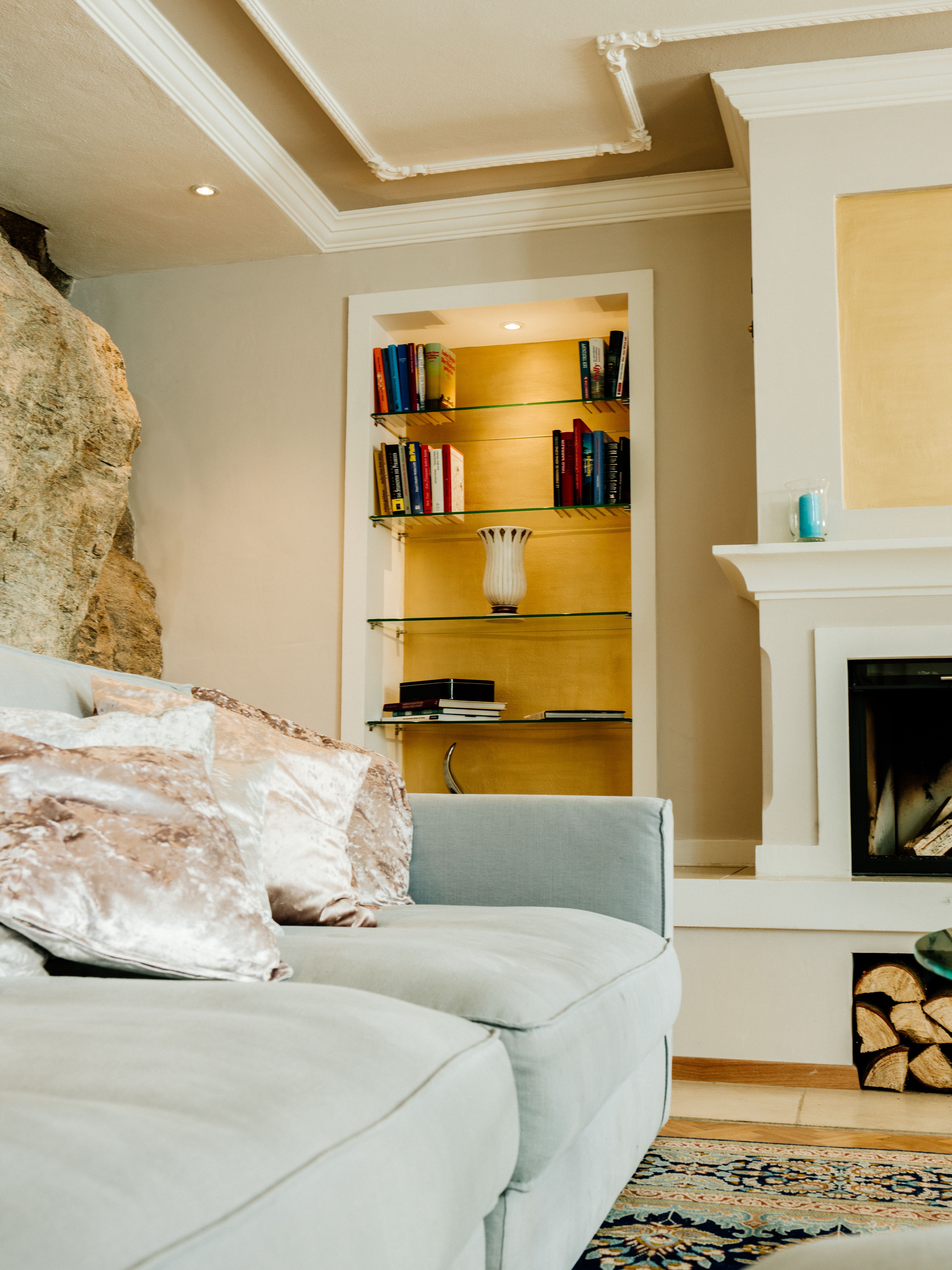 Elegantes Wohnzimmer mit grauem Sofa, Bücherregal und Kamin.