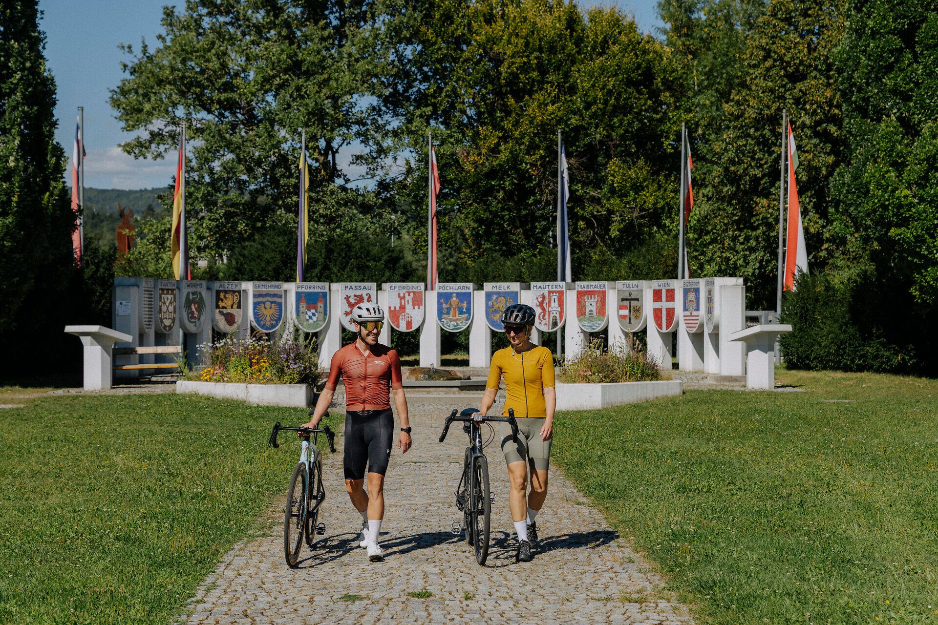 2 Kerékpárosok a Nibelungen emlékmű előtt Pöchlarnban, a Nibelungengau régióban