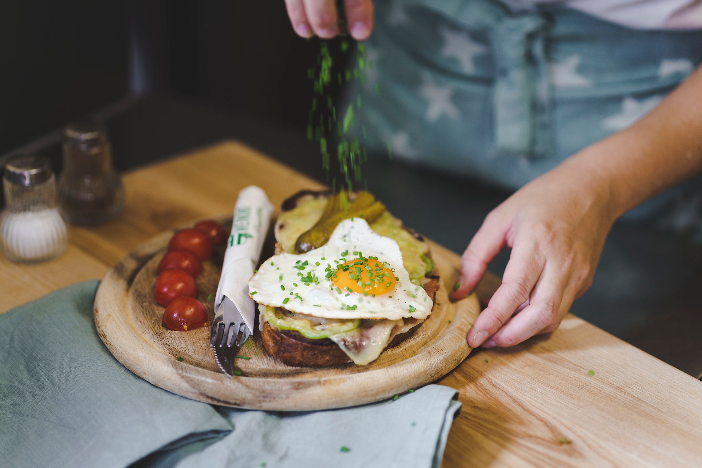 A plate with a sandwich, fried egg and tomatoes, garnished with chives.