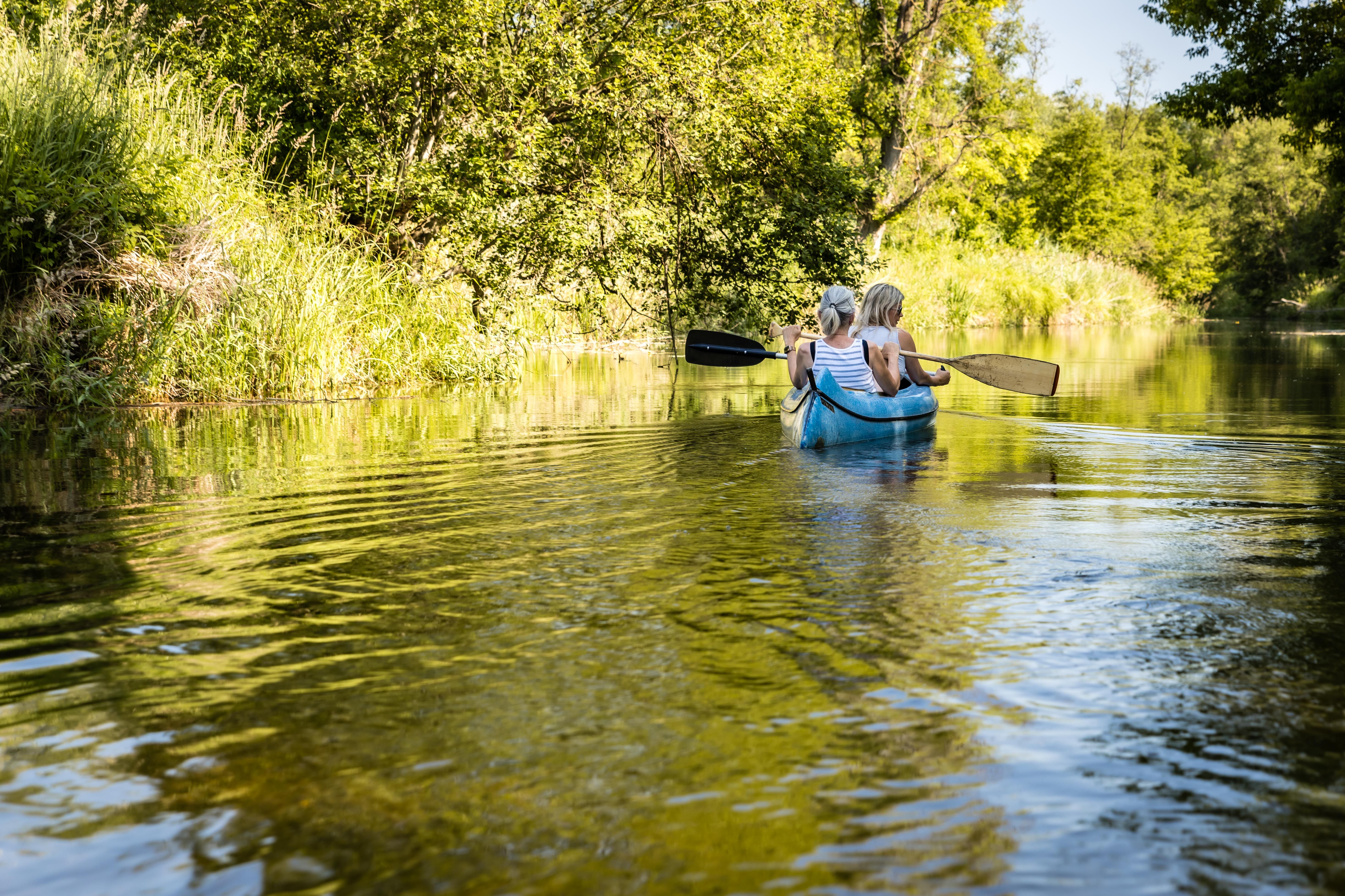 Familie im Kanu auf einem Fluss im Grünen.