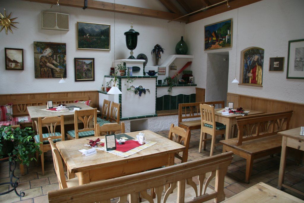 Gemütlicher Gastraum mit Holzmöbeln und dekorativen Gemälden an den Wänden.