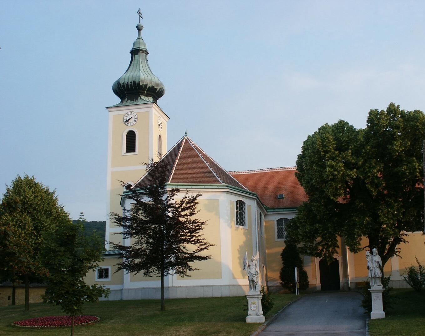 Wallfahrtskirche Wolfsthal mit Turm und Statuen im Vordergrund.
