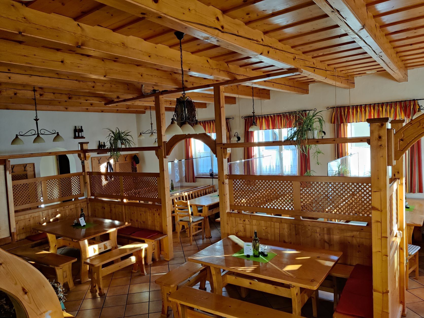 Innenansicht eines rustikalen Heurigenlokals mit Holzmöbeln und Pflanzen.