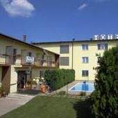 Außenansicht eines gelben Hotels mit Pool und Garten.