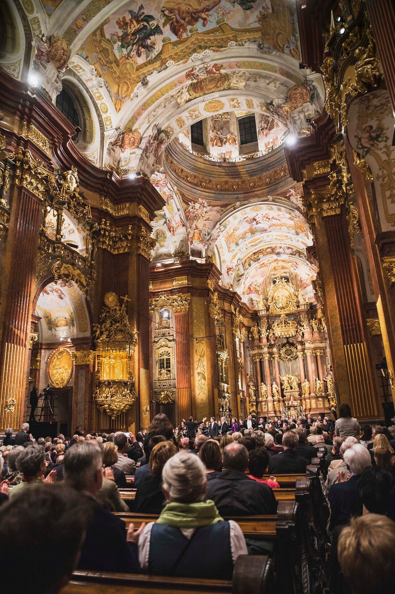 Die majestätische Barockarchitektur des Stifts Melk erstrahlt im warmen Licht der Abenddämmerung, während die Besucher gebannt den Klängen der Musik lauschen. Die opulente Innenausstattung und die kunstvollen Fresken schaffen eine Atmosphäre der Ehrfurcht und des Staunens, die jeden in ihren Bann zieht.