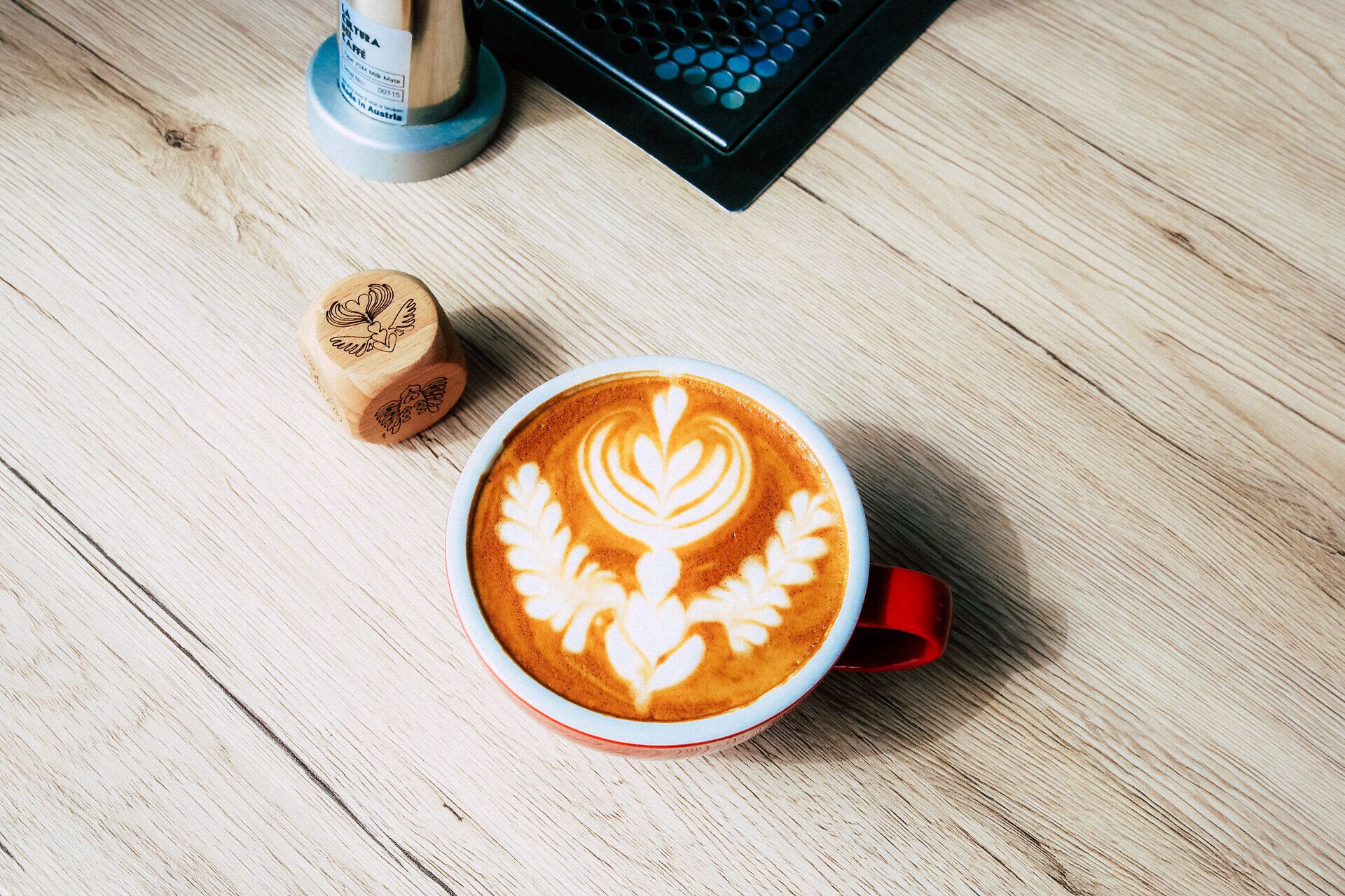 Tasse Cappuccino mit kunstvoller Latte Art auf einem Holztisch.