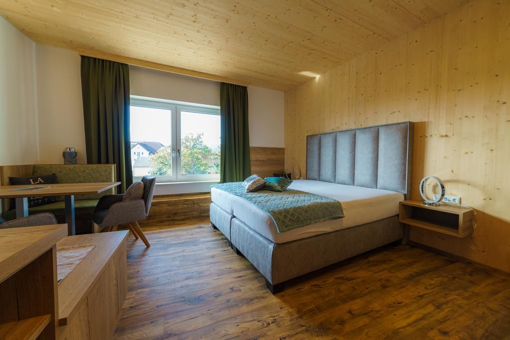 Modernes Hotelzimmer mit Doppelbett, Holzwänden und großem Fenster.