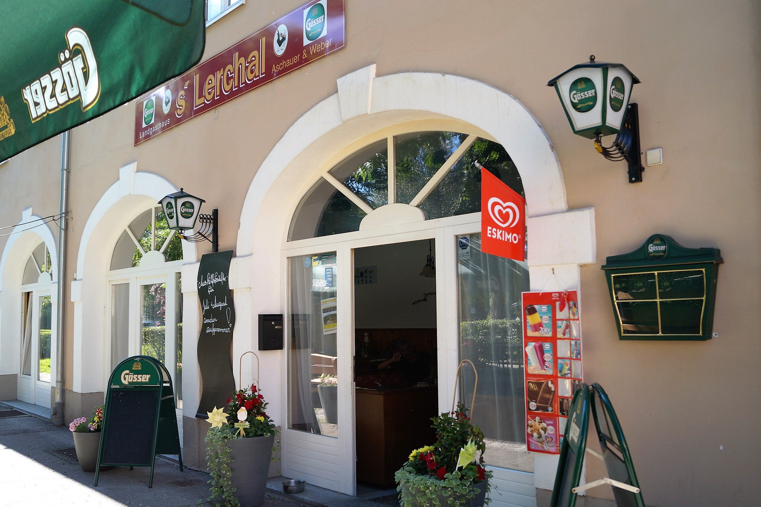 Außenansicht eines Restaurants mit Gösser-Schildern und Eskimo-Eiswerbung.