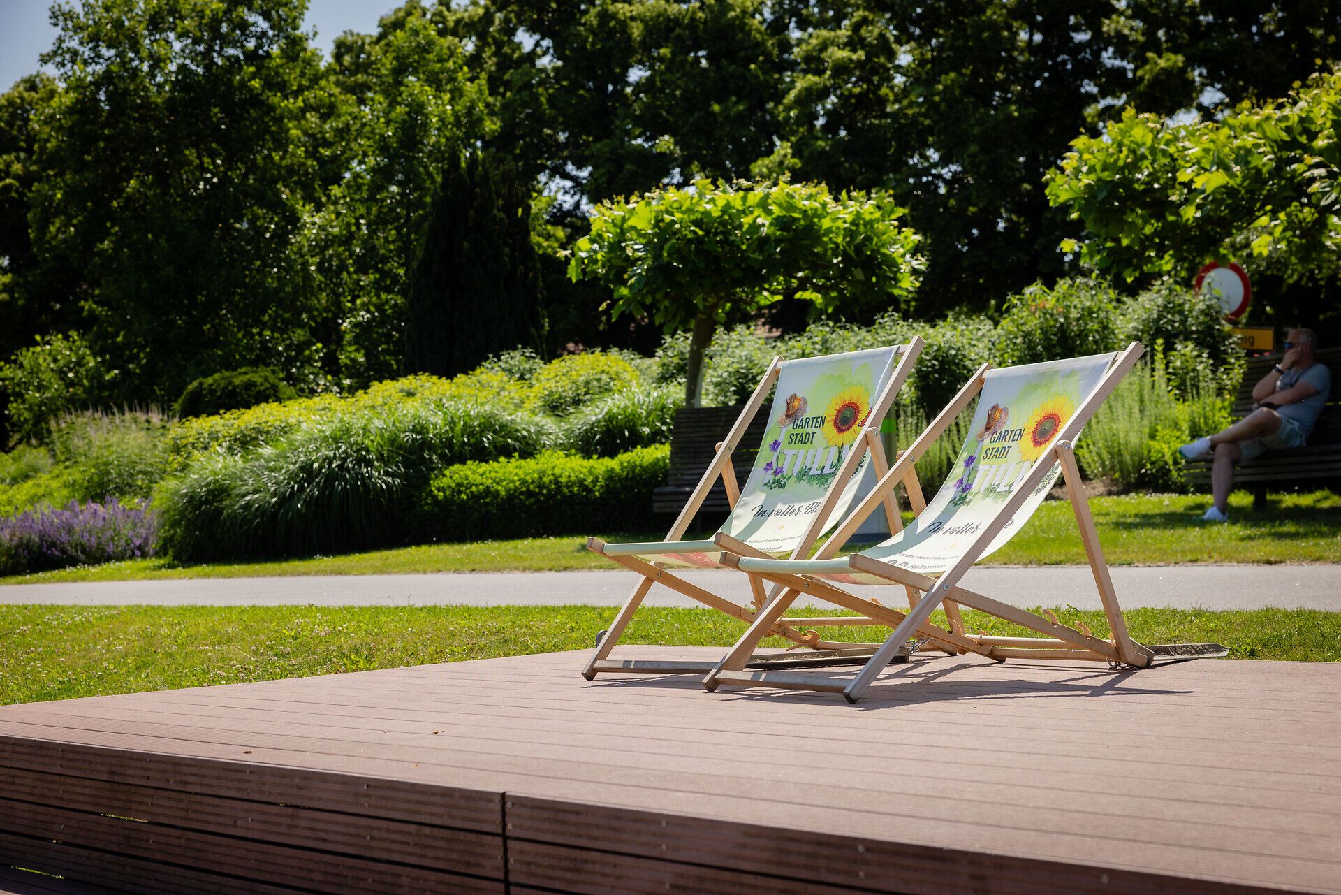 Zwei Liegestühle auf einem Podest, im Hintergrund viel Grün der Donaulände