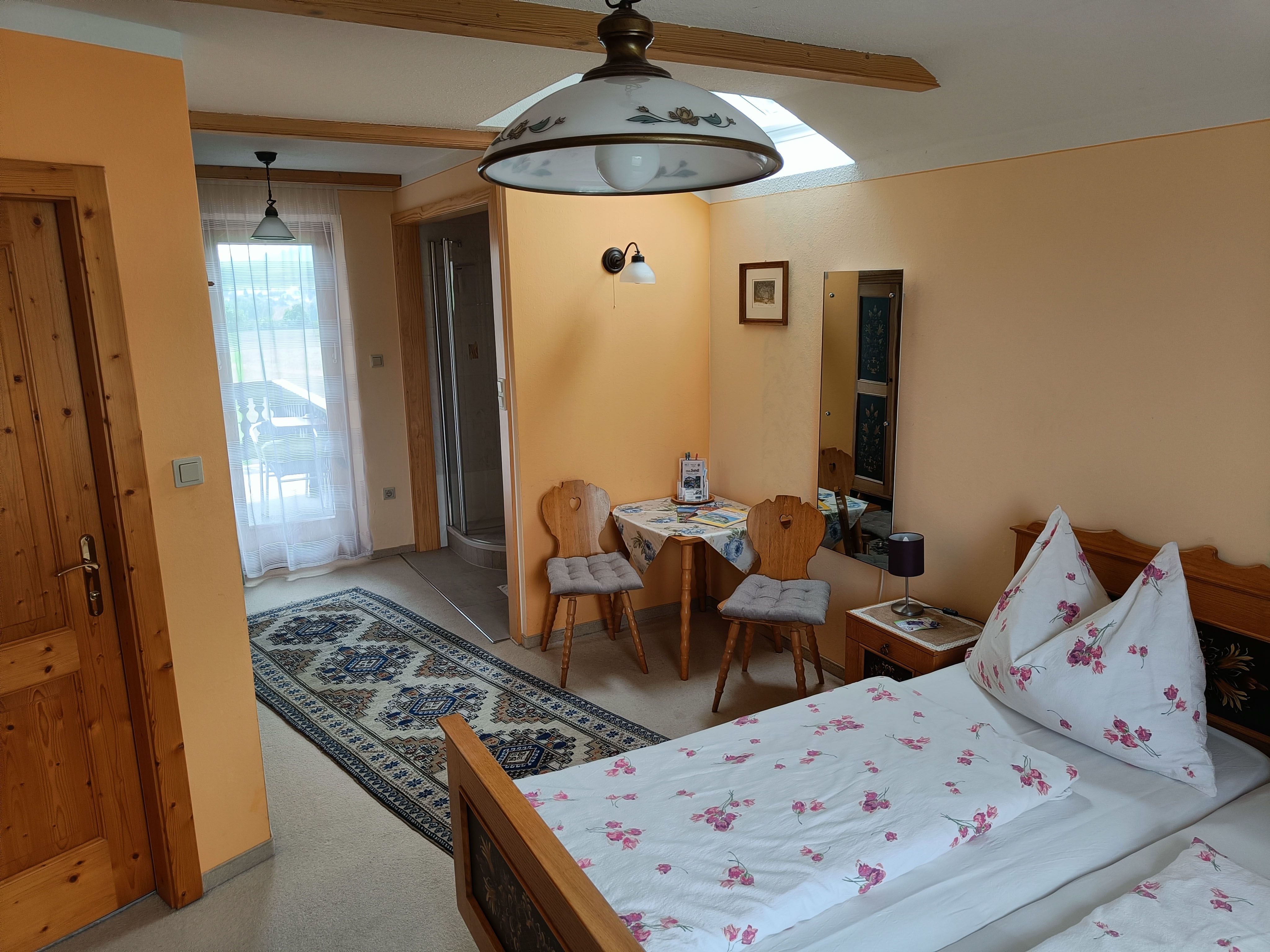 Zimmer mit Bett, Tisch und 2 Stühlen