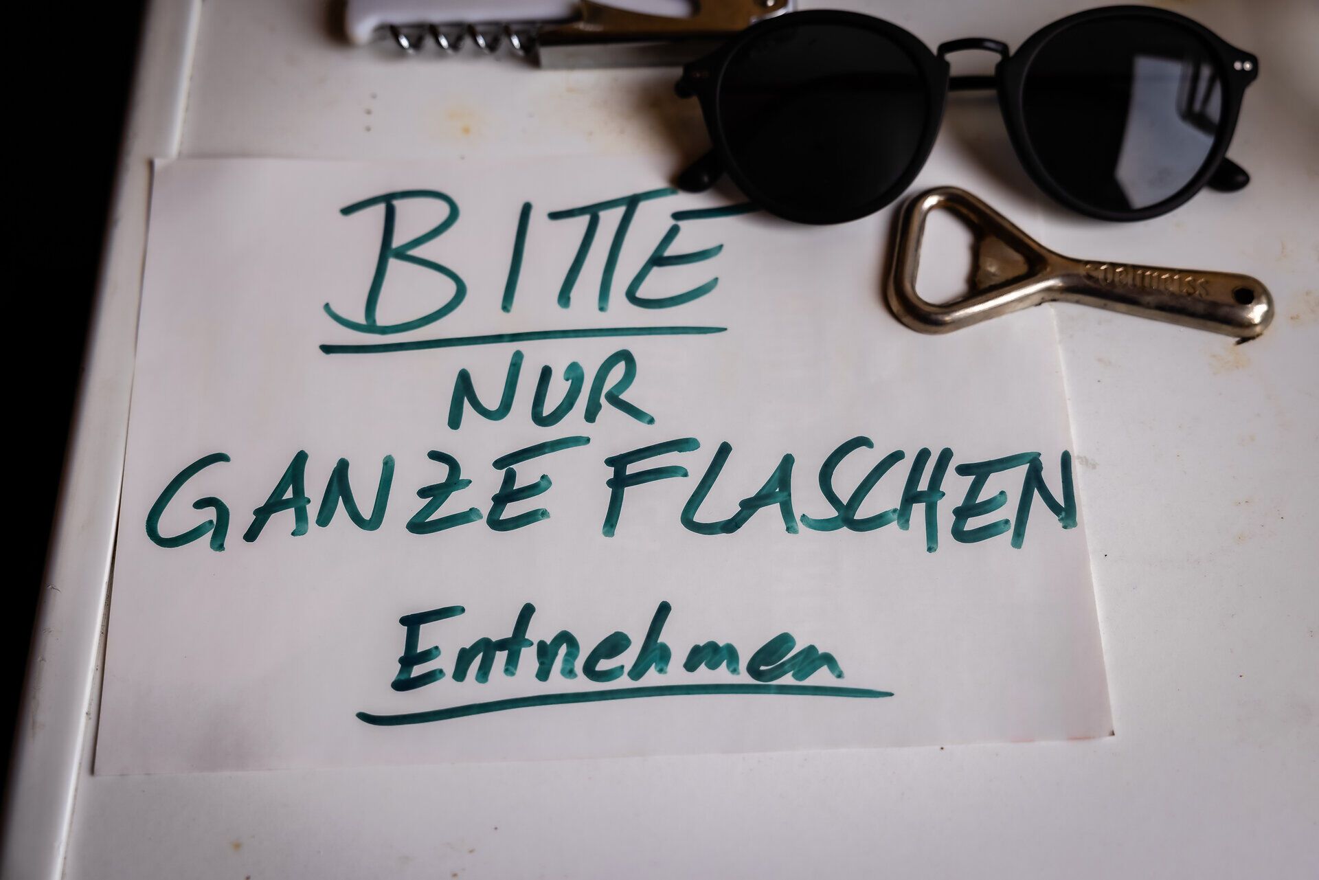 Korkenzieher, Bieröffner, Sonnenbrille und ein Zettel mit dem Schriftzug: Bitte nur ganze Flaschen entnehmen.