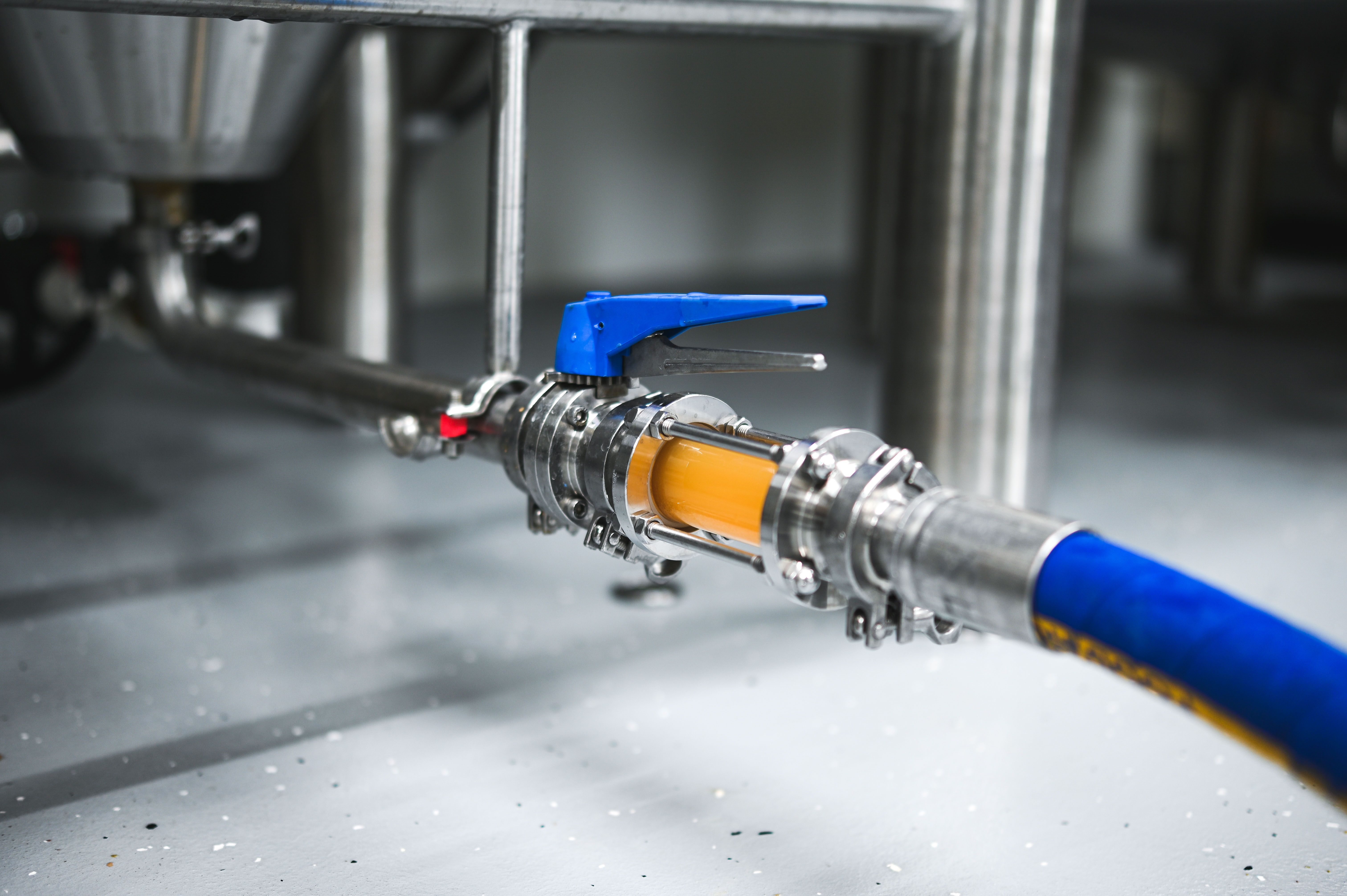 Nahaufnahme eines Brauereischlauchs mit Ventil und durchfließender Flüssigkeit.