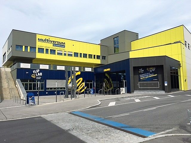 Außenansicht des Multiversum Schwechat, einem modernen Gebäude mit gelben und blauen Fassaden.