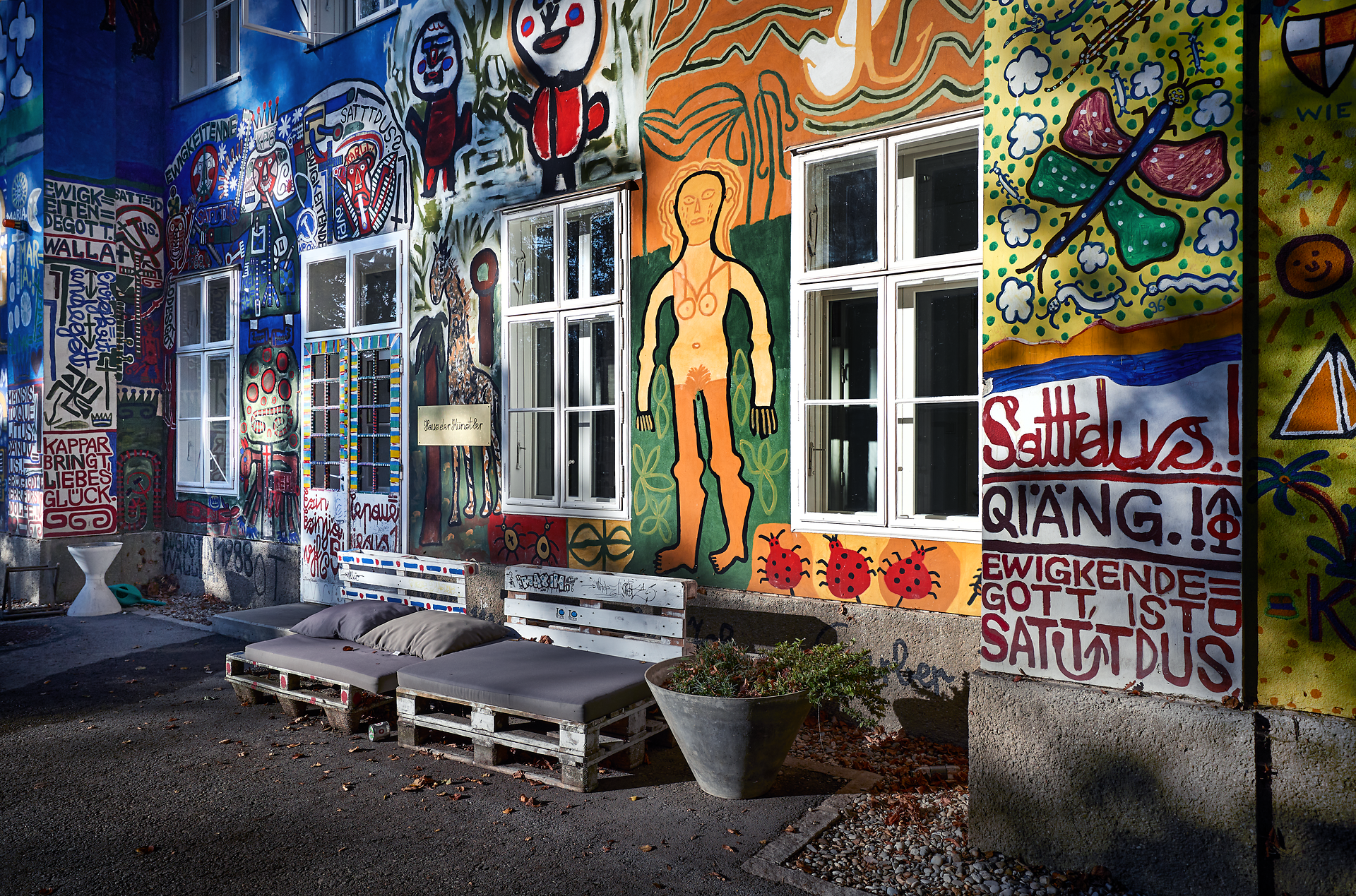 Bunte Wandmalereien und kreative Kunstwerke verleihen diesem Ort eine lebendige Atmosphäre. Die einladenden Sitzgelegenheiten laden dazu ein, die inspirierende Umgebung zu genießen und die Kunst in Ruhe zu betrachten. Hier verschmelzen Kreativität und Natur zu einem einzigartigen Erlebnis.