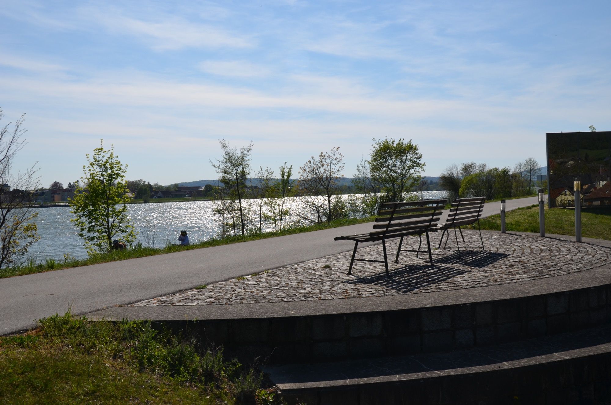 Zwei Bänke mit Blick auf einen Fluss bei sonnigem Wetter.