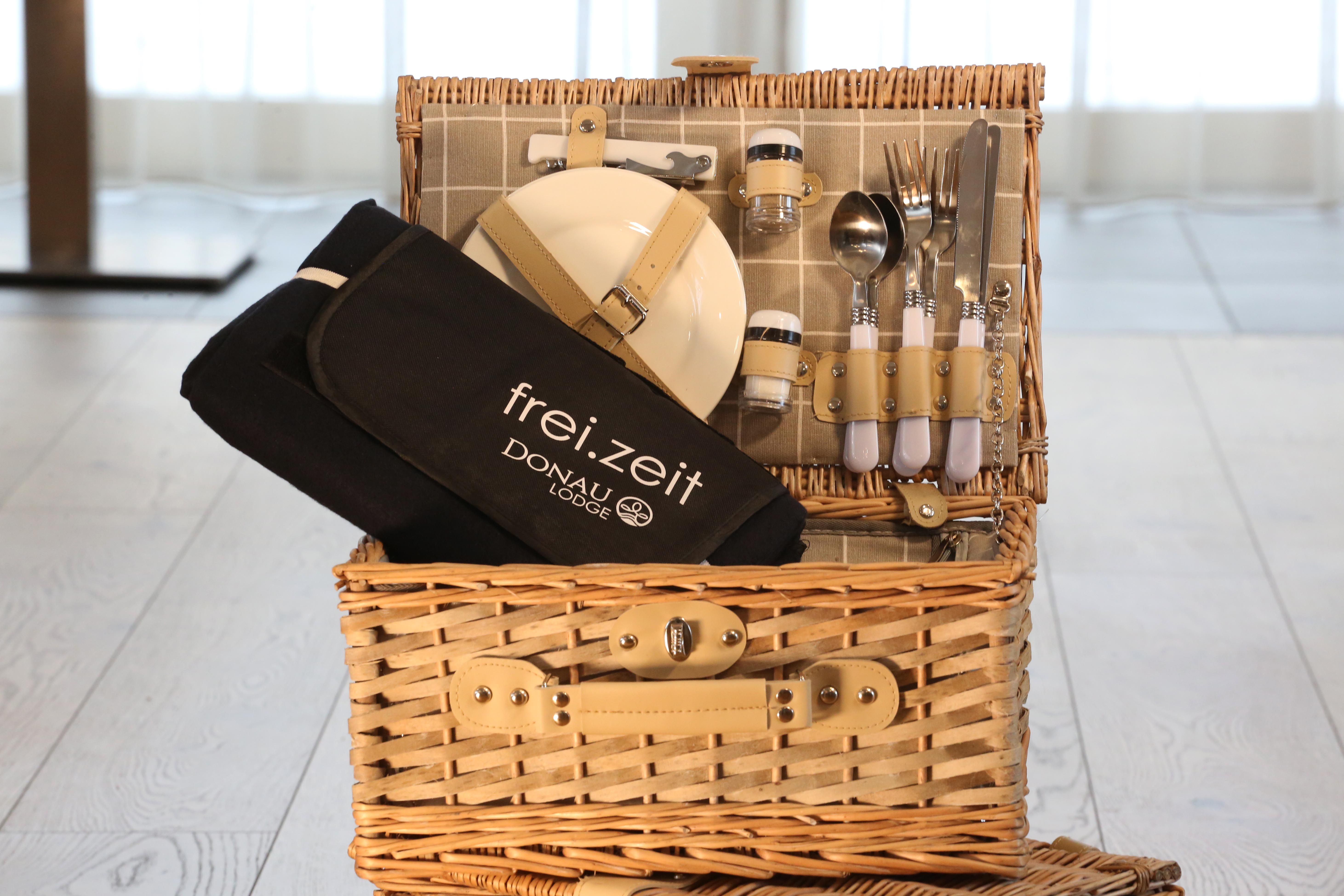 Ein heller Picknickkorb aus Holz aufgeklappt mit Utensilien