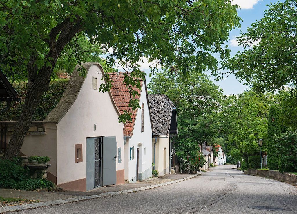 Malebná sklepní ulička s tradičními domy a stromy ve Stixneusiedlu v Dolním Rakousku
