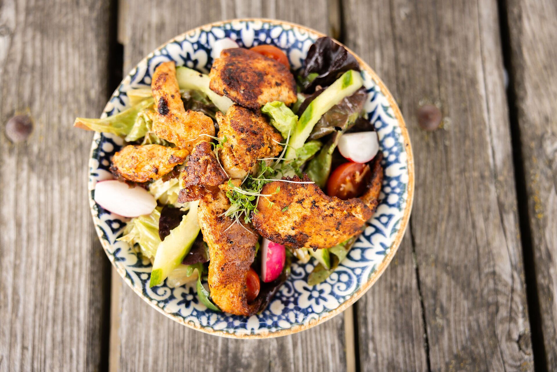 Gegrilltes Fleisch mit Salat auf einem bunten Teller.