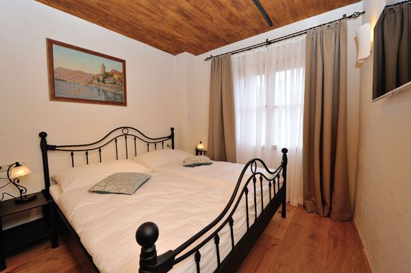 Schlafzimmer mit Metallbett, Holzboden und Gemälde an der Wand.