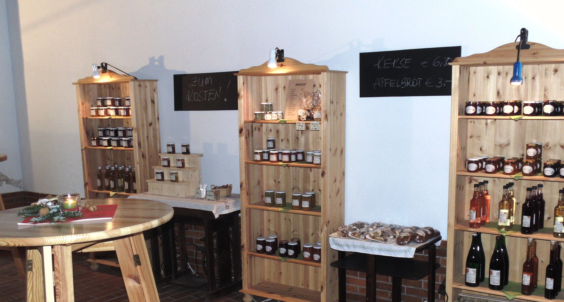 Innenansicht eines Hofladens mit Regalen voller Marmeladen, Säften und Keksen.