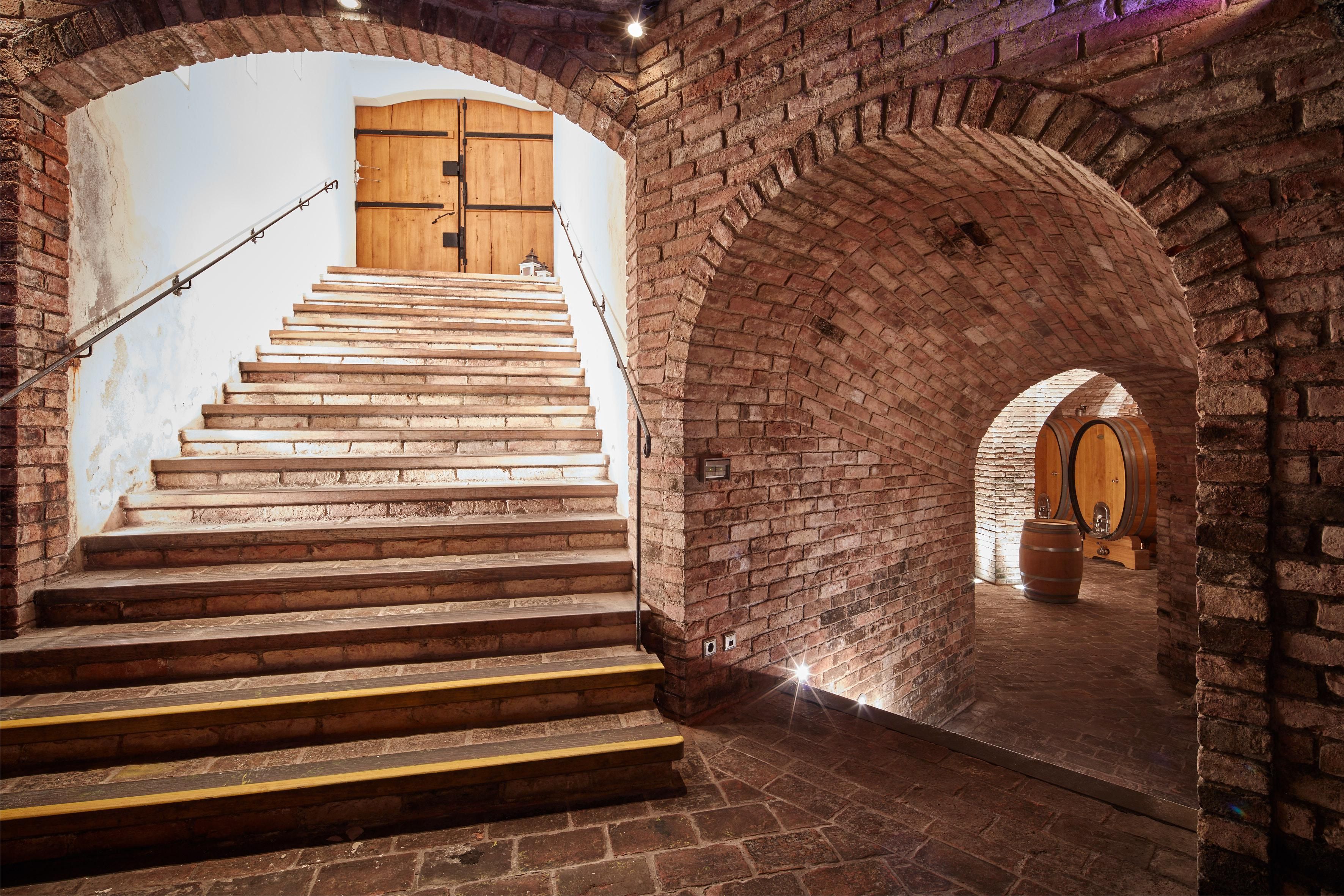 Der Gewölbekeller der Winzer Krems mit Treppen und einem Rundbogen aus roten Ziegelsteinen.