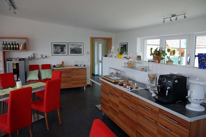 Frühstücksraum mit roten Stühlen, Holzmöbeln und Kaffeemaschine.