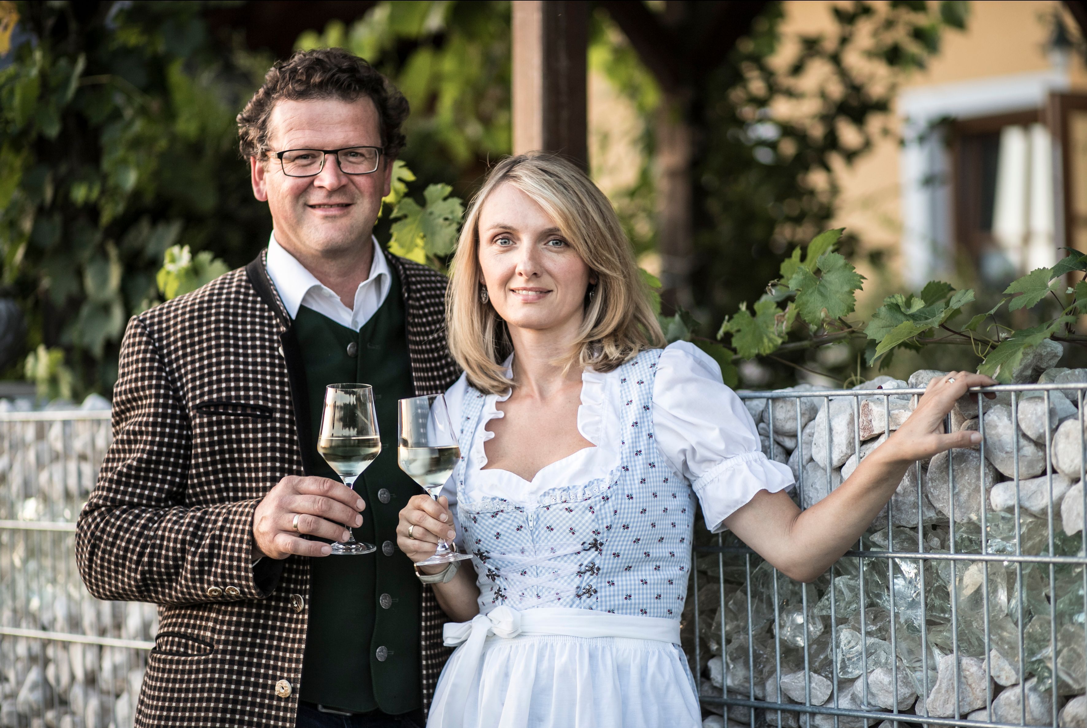 Ein Mann und eine Frau in traditioneller Kleidung halten Weingläser in der Hand.