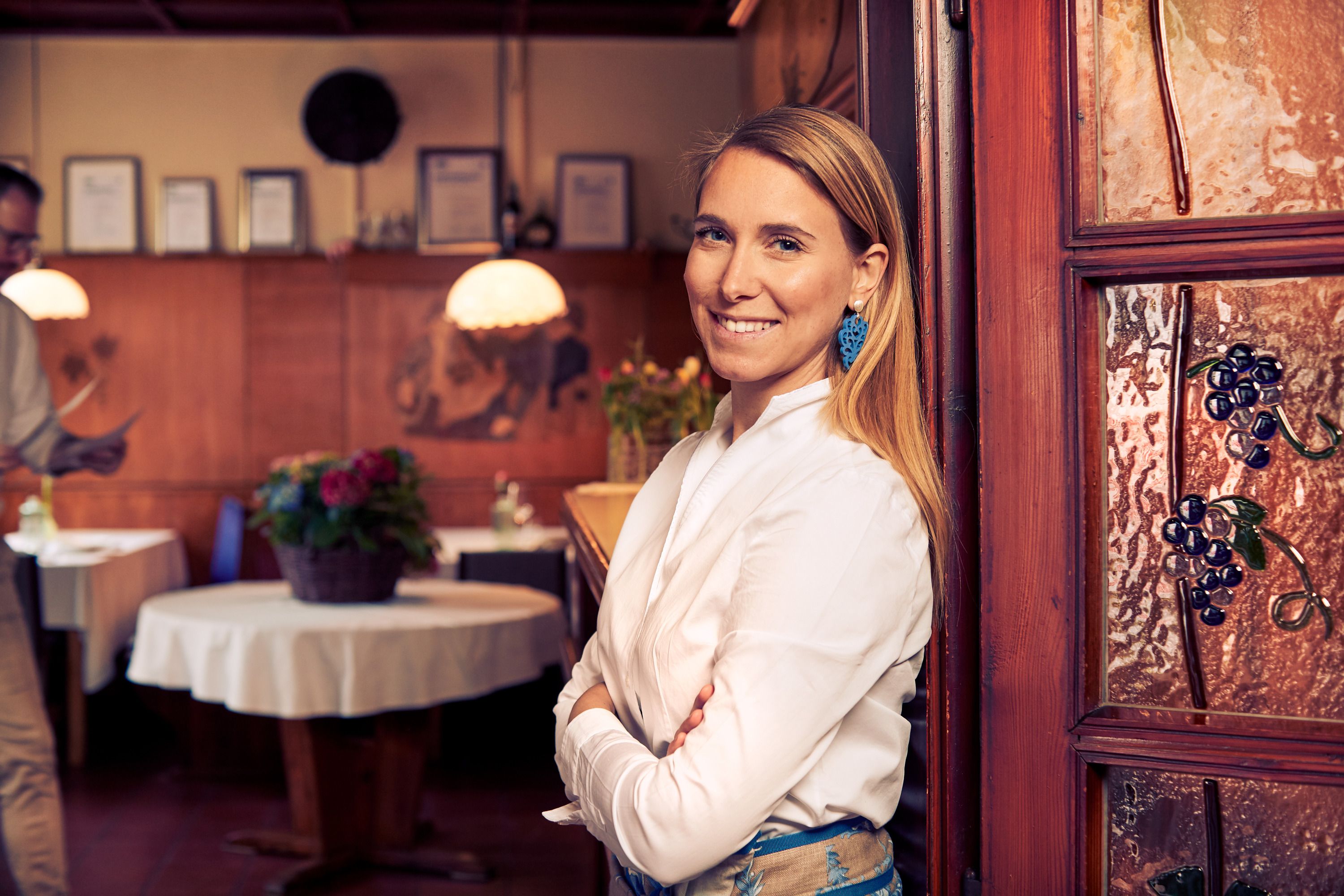 Frau in weißem Hemd lächelt in traditionellem Restaurant mit Holzeinrichtung.