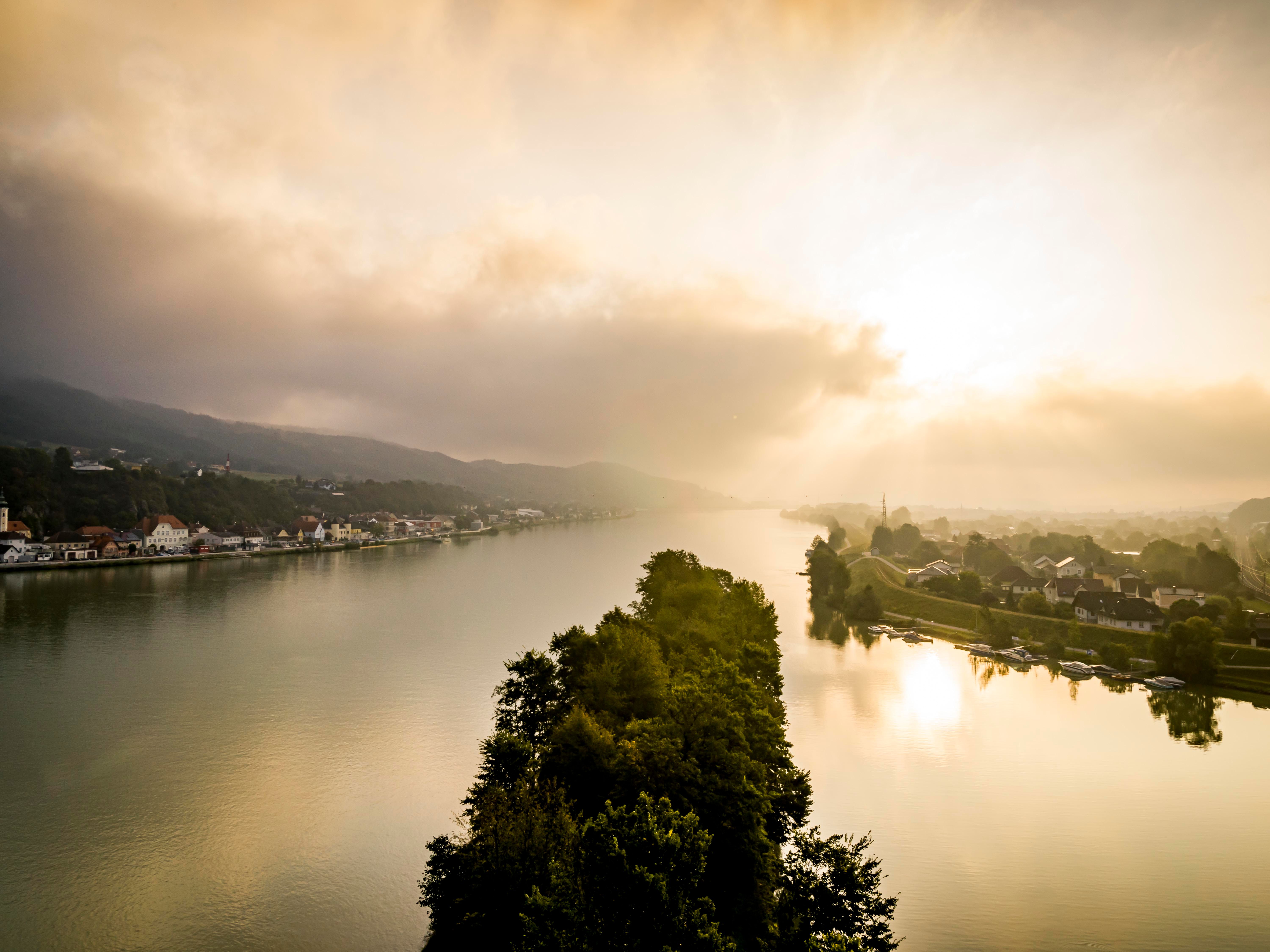 Luftaufnahme von Krummnußbaum und Marbach bei Sonnenaufgang mit Fluss und bewölktem Himmel.